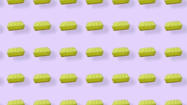 Buntes Muster aus gelben Küchenschwämmen auf lila Hintergrund mit Schatten. Nahtloses Muster mit Schwamm. Ansicht von oben. Realistische Animation. 4K-Videobewegung — Stockvideo