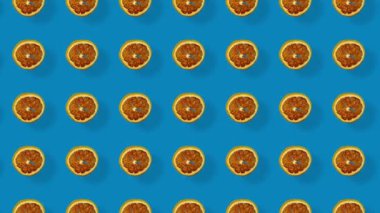 Mavi arka planda gölgeli kurutulmuş greyfurt dilimlerinin renkli deseni. Kurutulmuş greyfurt parçacıklarıyla kusursuz desen. Gerçekçi animasyon. 4K video hareketi