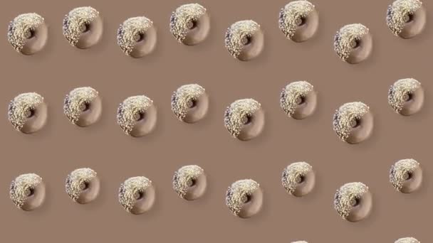 Kleurrijk patroon van chocolade donuts geïsoleerd op bruine achtergrond met schaduwen. Naadloos patroon met donut. Donuts. Bovenaanzicht. Realistische animatie. 4K video beweging — Stockvideo
