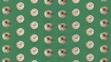 Yeşil arka planda izole edilmiş renkli donut deseni. Donutla kusursuz desen. Çörekler. Üst Manzara. Gerçekçi animasyon. 4K video hareketi