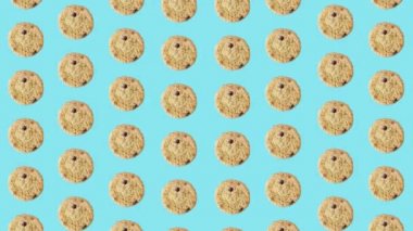 Mavi arka planda taze çikolatalı kurabiyelerin renkli deseni. Kurabiyeyle kusursuz desen. Üst Manzara. Gerçekçi animasyon. 4K video hareketi