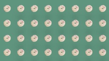 Yeşil arka planda izole edilmiş renkli donut deseni. Donutla kusursuz desen. Çörekler. Üst Manzara. Gerçekçi animasyon. 4K video hareketi