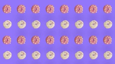 Mor arka planda izole edilmiş renkli donut deseni. Donutla kusursuz desen. Çörekler. Üst Manzara. Gerçekçi animasyon. 4K video hareketi