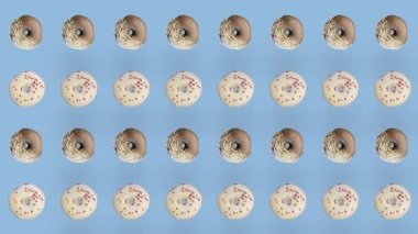 Mavi arka planda izole edilmiş renkli donut deseni. Donutla kusursuz desen. Çörekler. Üst Manzara. Gerçekçi animasyon. 4K video hareketi