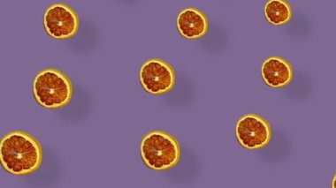 Mor arka planda gölgeli kurutulmuş greyfurt dilimlerinin renkli deseni. Kurutulmuş greyfurt parçacıklarıyla kusursuz desen. Gerçekçi animasyon. 4K video hareketi