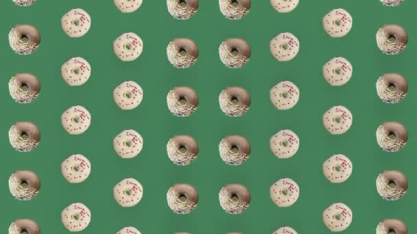 Padrão colorido de rosquinhas isoladas em fundo verde. Padrão sem costura com donut. Donuts. Vista superior. Animação realista. Movimento de vídeo 4K — Vídeo de Stock