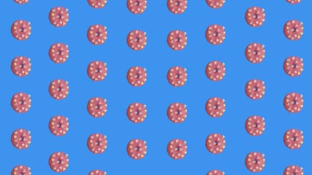 Πολύχρωμο μοτίβο ροζ ντόνατς που απομονώνονται σε μπλε φόντο. Απρόσκοπτο μοτίβο με ντόνατ. Ντόνατς. Στο πάνω μέρος. Ρεαλιστική κίνηση. 4K κίνηση βίντεο — Αρχείο Βίντεο