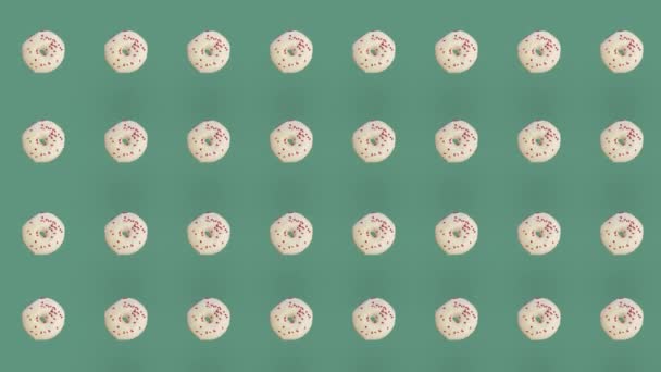 Patrón colorido de rosquillas aisladas sobre fondo verde. Patrón sin costuras con rosquilla. Rosquillas. Vista superior. Animación realista. Movimiento de vídeo 4K — Vídeo de stock