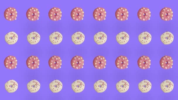 Красочный рисунок пончиков выделен на фиолетовом фоне. Бесшовный рисунок с пончиком. Пончики. Вид сверху. Реалистичная анимация. 4K видео движение — стоковое видео