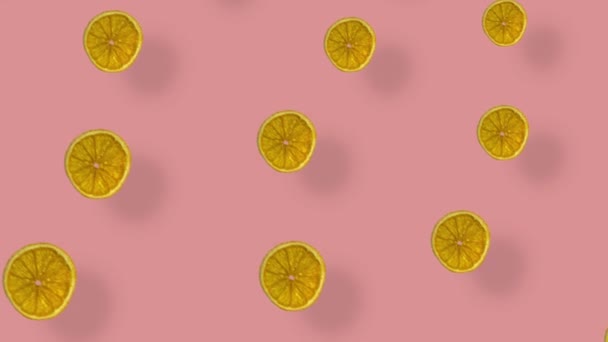 Kleurrijk patroon van gedroogde sinaasappelschijfjes op roze ondergrond met schaduwen. Naadloos patroon met gedroogde oranje chips. Realistische animatie. 4K video beweging — Stockvideo