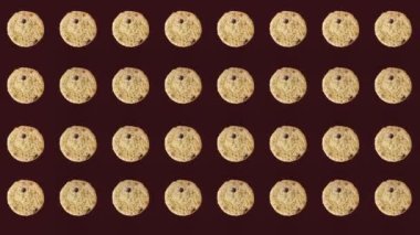 Koyu arkaplanda taze çikolatalı kurabiyelerin renkli deseni. Kurabiyeyle kusursuz desen. Üst Manzara. Gerçekçi animasyon. 4K video hareketi