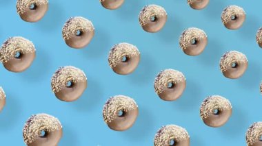Mavi arka planda gölgeli renkli çikolatalı donut deseni. Donutla kusursuz desen. Çörekler. Üst Manzara. Gerçekçi animasyon. 4K video hareketi