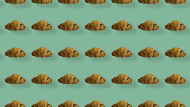 Colorful pattern of croissants on green background with shadows. Seamless pattern with croissant. Top view. Realistic animation. 4K video motion — Stockvideo