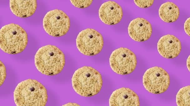 Kleurrijk patroon van verse chocolade chip koekjes op roze achtergrond. Naadloos patroon met koekje. Bovenaanzicht. Realistische animatie. 4K video beweging — Stockvideo
