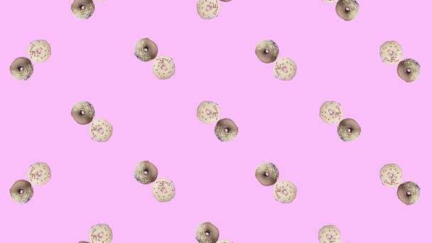 Барвистий візерунок обертаються пончики ізольовані на рожевому фоні. Безшовний візерунок з пончиком. Дуанти. Вид зверху. Реалістична анімація. Рух відео 4K — стокове відео
