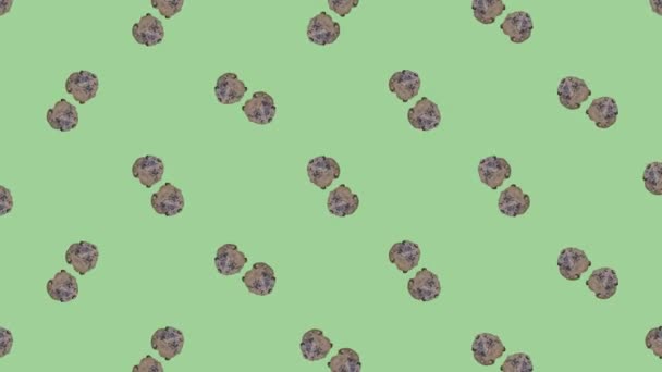 Colorful pattern of fresh rotating chocolate chip cookies on green background. Seamless pattern with cookie. Top view. Realistic animation. 4K video motion — Stockvideo