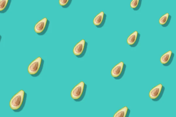 Buntes Muster frischer Avocados auf türkisfarbenem Hintergrund mit Schatten. Ansicht von oben. Flach lag er. Pop-Art-Design — Stockfoto