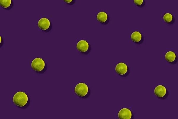Barevný ovocný vzor čerstvých limetek na fialovém pozadí se stíny. Horní pohled. Ležel. Pop art design — Stock fotografie