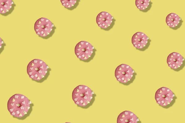 Colorful pattern of pink glazed donuts isolated on yellow background with shadows. Doughnuts. Top view. Flat lay — Stock Photo, Image