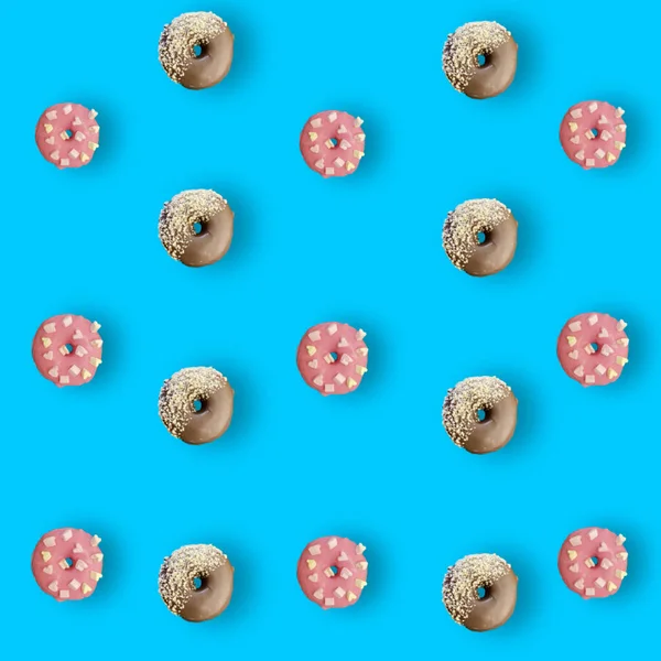 Kleurrijk patroon van chocolade en roze geglazuurde donuts geïsoleerd op blauwe achtergrond met schaduwen. Donuts. Bovenaanzicht. Vlakke plaat — Stockfoto