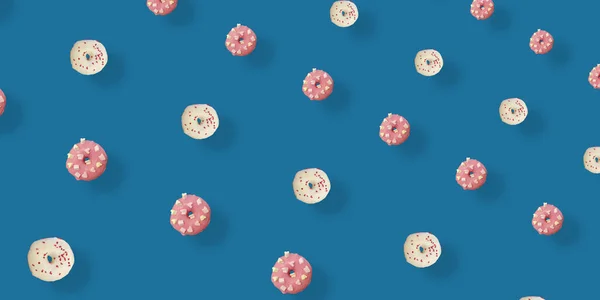 Modello colorato di ciambelle smaltate bianche e rosa isolate su sfondo blu con ombre. Ciambelle. Vista dall'alto. Posa piatta — Foto Stock