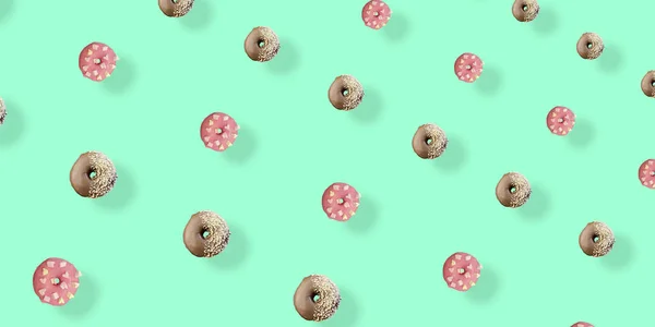 Kolorowy wzór czekolady i różowe pączki szkliwione izolowane na zielonym tle z cieniami. Pączki. Widok góry. Układy płaskie — Zdjęcie stockowe