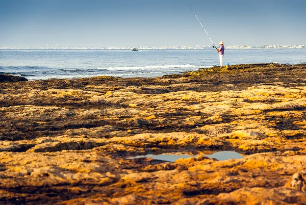 Costa rocosa y ver con pescador —  Fotos de Stock