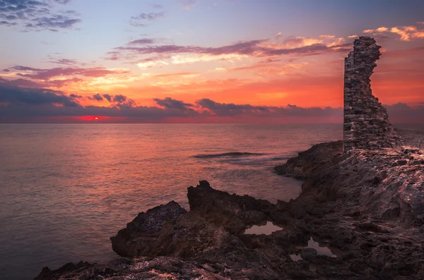 Tramonto sul mare e costa rocciosa con antiche rovine — Foto Stock