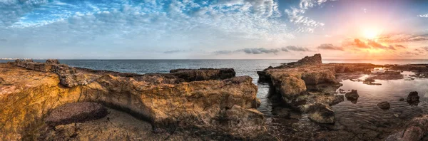 海和岩石海岸，与古代遗址上空的日落 — 图库照片