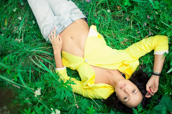 Schönes Mädchen auf einem Gras liegend — Stockfoto