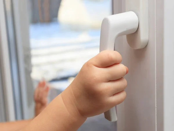 Çocuk pencerenin sapına tutunarak açmaya çalışıyor. Sadece çocukları evde bırakma kavramı, çocukların güvenliği, ebeveynsiz çocuklar....