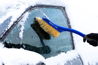 Kışın arabayı kardan temizlemek. Kar yağışı sonrası karla kaplı araba. Kışın sert hava koşulları, kar fırtınası ve kötü hava koşulları. Çok şiddetli bir kar fırtınası var. Araç karla kaplı..