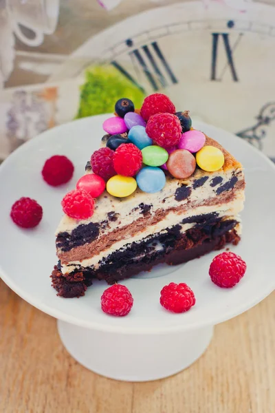 Triple chocolate cheesecake with raspberries and candies — Stock Photo, Image