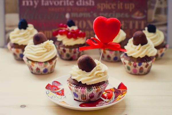 Vanilla cupcakes with cream cheese frosting, chocolate and berries with heart decorating — Stock Photo, Image