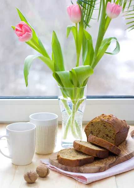 Walnut cake with tulips near the window — Stock Photo, Image