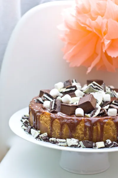 Slice of cheesecake with chocolate ganashe, decorated with mini marshamallows, cookies and chocolate — Stock Photo, Image