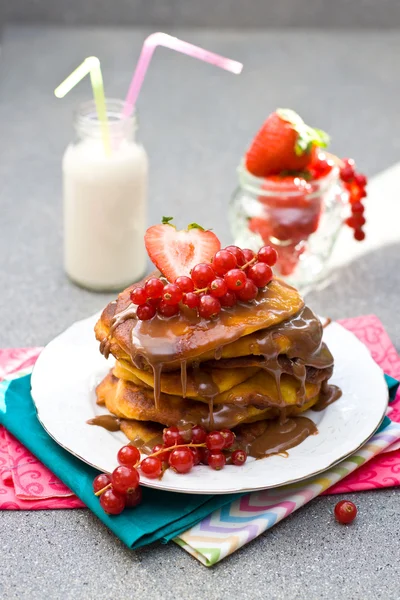 Crêpes à la sauce caramel, groseille rouge et fraises et verre de lait sur fond gris — Photo