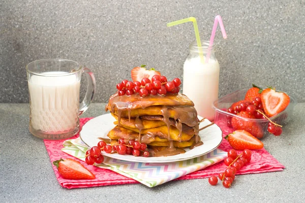 キャラメル ソース、赤スグリ、イチゴ、灰色の背景上のミルクのガラスを持つパンケーキ — ストック写真