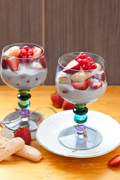 Vanille pudding met vanille zaden, verse aardbeien, rode bessen en savoiardi cookies in blauw gekleurde bril — Stockfoto