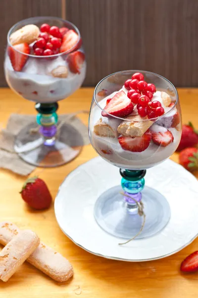 Vanille pudding met vanille zaden, verse aardbeien, rode bessen en savoiardi cookies in blauw gekleurde bril — Stockfoto