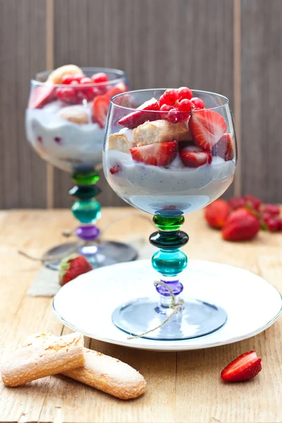 Vanille pudding met vanille zaden, verse aardbeien, rode bessen en savoiardi cookies in blauw gekleurde bril — Stockfoto