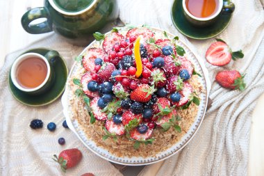 Napolyon kek, taze çilek, çilek, yaban mersini ve doğum günü mumu ile böğürtlen ile dekore edilmiştir. çaydanlık ve bardak yeşil çay iki pencere yakın:.