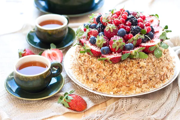 Napolyon kek, taze çilek, çilek, yaban mersini ve doğum günü mumu ile böğürtlen ile dekore edilmiştir. çaydanlık ve bardak yeşil çay iki pencere yakın:.