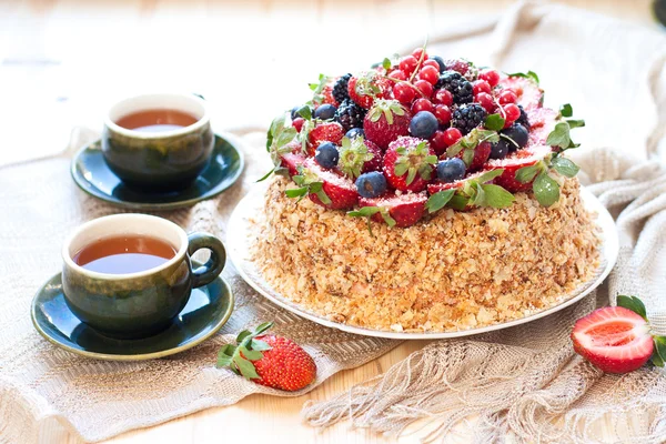 Napoleon gebak, ingericht met verse bessen, aardbeien, bosbessen en braambessen, met verjaardag kaars. twee kopjes groene thee en theepot in de buurt van het venster. — Stockfoto