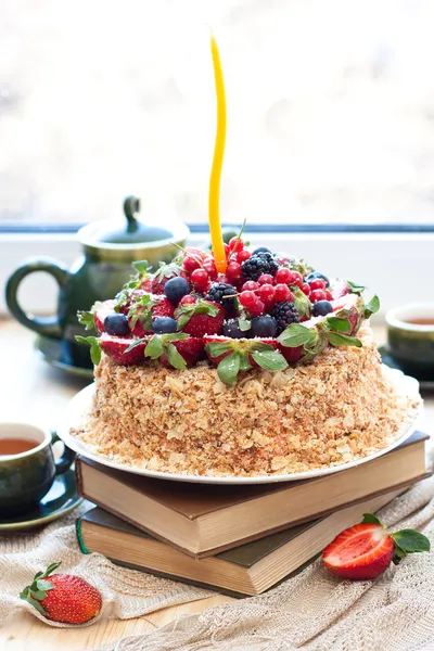 Napoleon cake, decorated with fresh berries, strawberries, blueberries and blackberries, with birthday candle. Two green tea cups and teapot near the window. — Stock Photo, Image