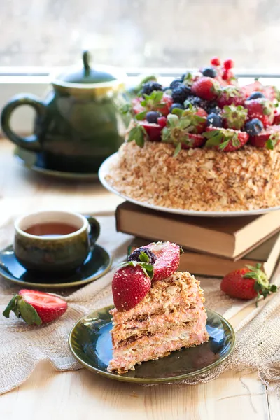 Napoleon gebak, ingericht met verse bessen, aardbeien, bosbessen en braambessen, met verjaardag kaars. twee kopjes groene thee en theepot in de buurt van het venster. — Stockfoto