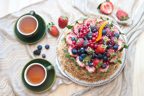 Pastel de Napoleón, decorado con bayas frescas, fresas, arándanos y moras, con vela de cumpleaños. Dos tazas de té verde y tetera cerca de la ventana . — Foto de Stock