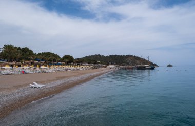 Dağ ve ufukta güneş gözlüklü, boş halk plajından gün doğumu manzarası. Akdeniz 'de bir gemi. Tekirova, Antalya Türkiye. Mayıs 2021
