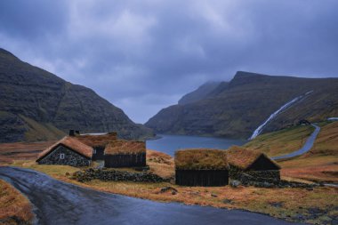 Dramatik Kasım manzarası. Faroe Adaları 'ndaki tipik çim çatılı evleri olan Saksun köyü manzarası. Danimarka, Avrupa 'daki Streymoy Adası' nın muhteşem sabah manzarası. 2021