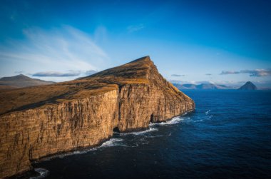 Faroe Adaları Traelanipa. Kölelerin kaya uçurumu okyanusun üzerinde Sorvagsvatn Gölü 'nün yanında yükseliyor. Sonbahar boyunca Faroe Adaları 'ndaki vajina adasında bulutlar ve mavi gökyüzü. Kasım 2021